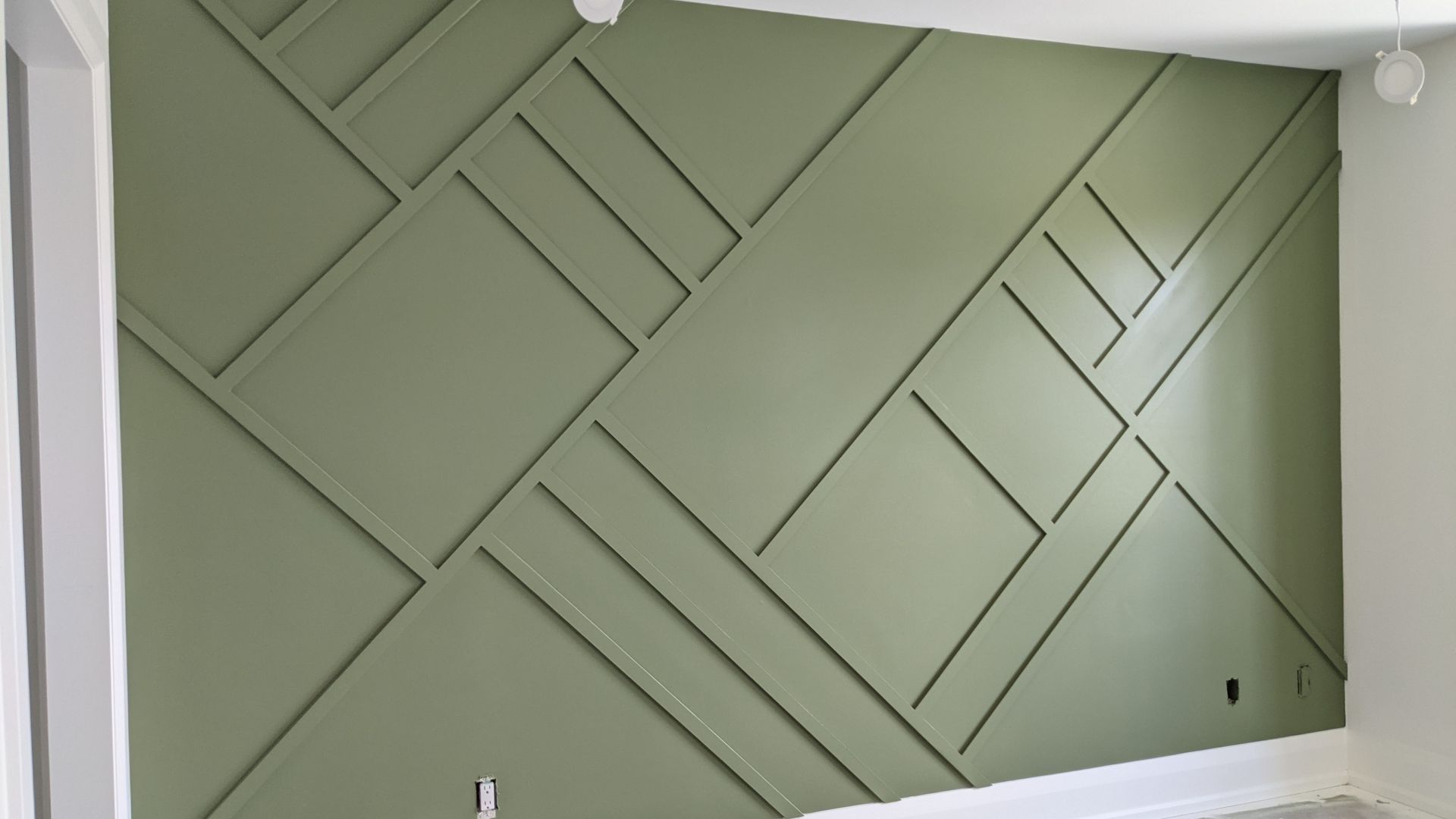 Green geometric feature wall with diagonal and horizontal moulding layout
