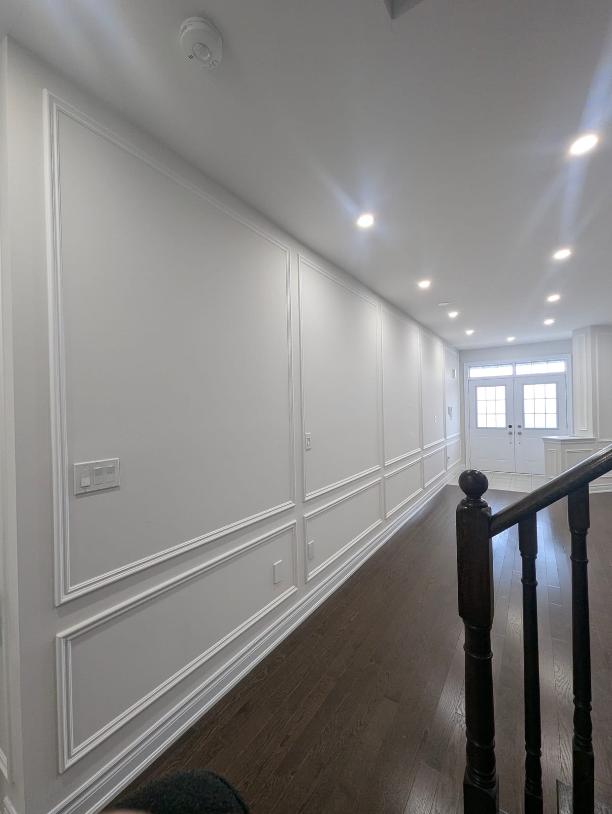 Full-height panel moulding along a Mississauga hallway beside the staircase railing