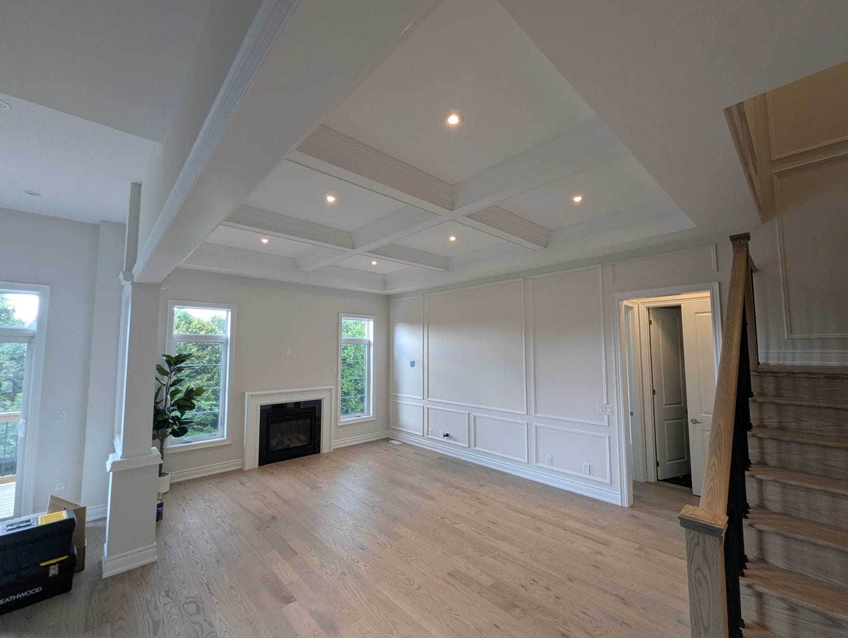 Coffered ceiling above a panelled wall and fireplace in an Oakville great room