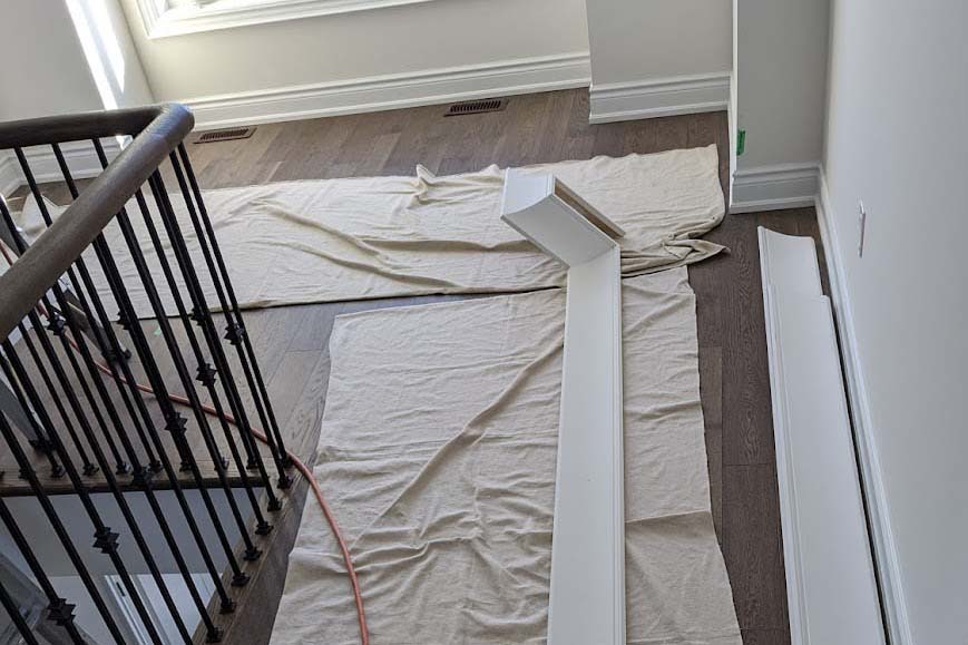 Drop-cloth floor protection during trim installation in luxury Toronto home